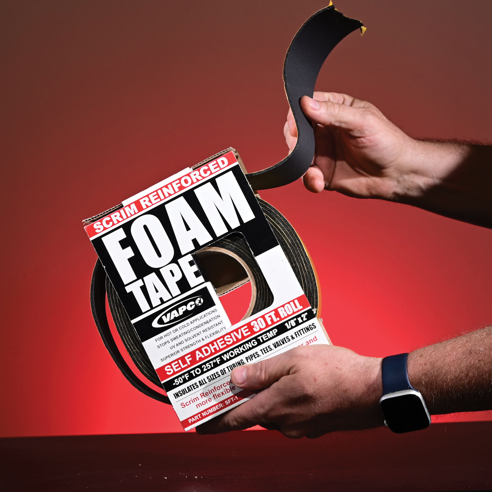 A person holding a box of scrim foam tape and pulling a long piece of the tape out of the box.