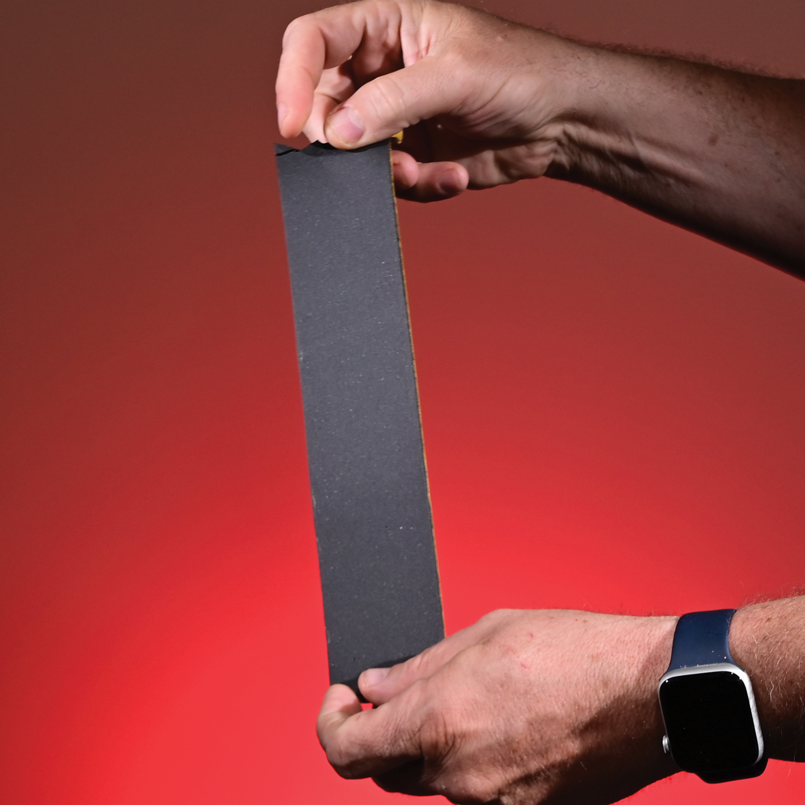 Close-up of the smooth, black front side of a piece of scrim foam tape.