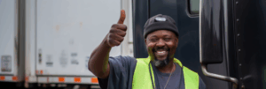 A dockworker with a thumbs-up gesture in front of a delivery truck, symbolizing the success and reliability of the Vapco Free Freight Program.