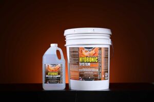 Studio image of a 1-gallon jug and a 5-gallon pale of Vapco Hydronic System Cleaner against an orange background.A gallon jug of Hydronic System Cleaner, a concentrated formula for cleaning closed-loop systems. Cleaning a Glycol Hydronic System