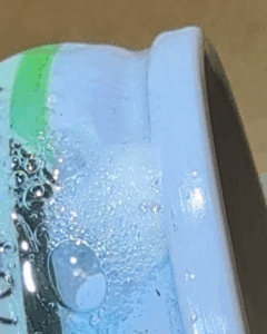 A close-up photo of a surface with Bird Dog Leak Detector applied, showing a pattern of sustained bubbles, indicating a slightly larger leak than a micro-leak.