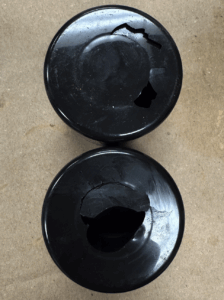 A close-up photo of an aerosol can's top, showing a distinct crack in the plastic cap.